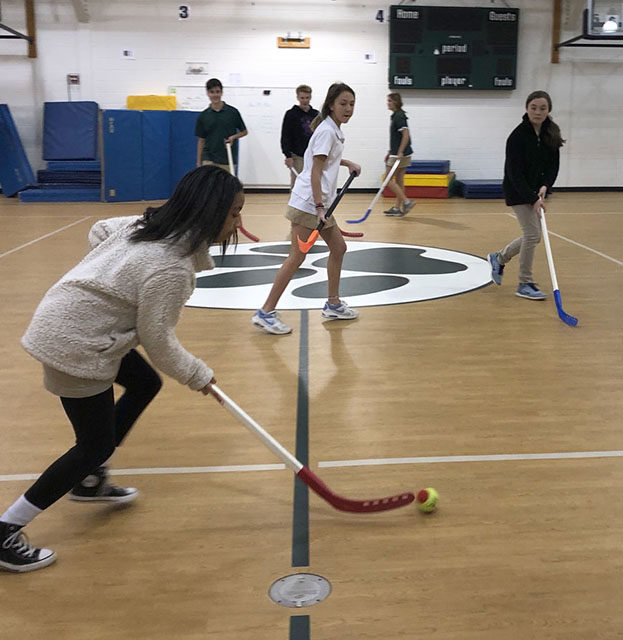 ACDS athletics students practicing field hockey in gym