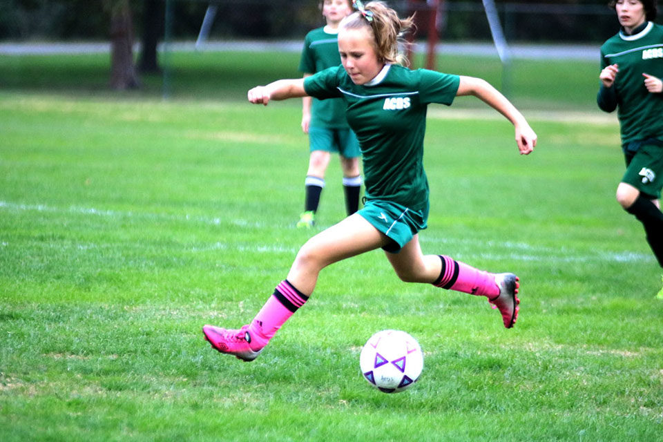 ACDS athletics female soccer player running next to ball