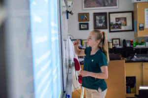 ACDS science female student writing on dry erase board
