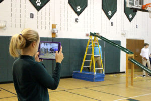 ACDS technology teacher with ipad recording experiment in gym